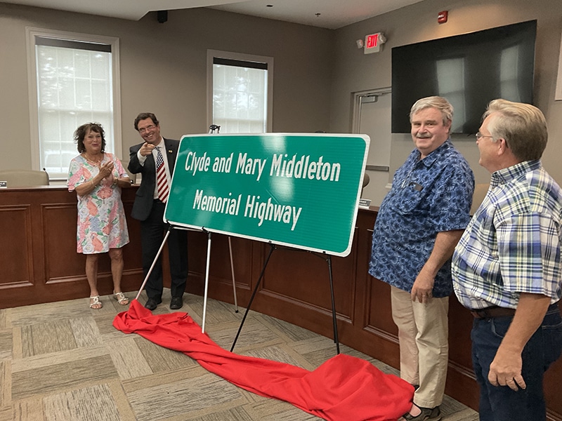 Four people stand at a sign that has been unveiled