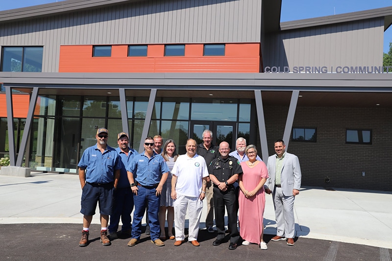 group of people stand in front of new community center building