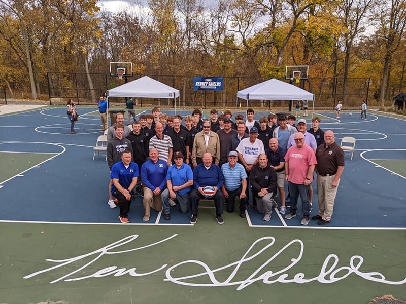 Group of about 30 people seated on a basketball court