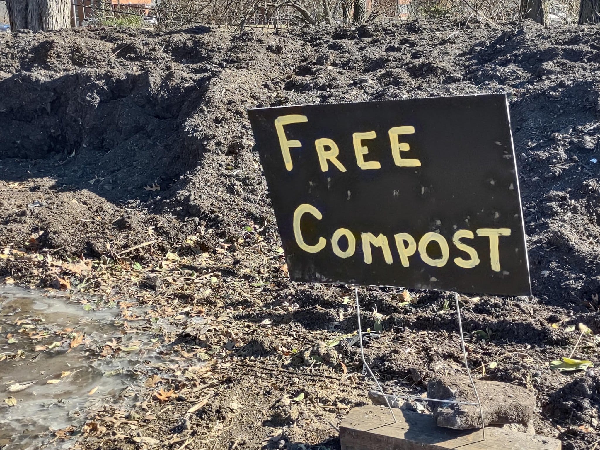 A sign "Free Compost" stuck into a pile of compost dirt.