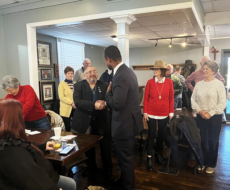 Crowd of people in restaurant with candidate shaking hands.