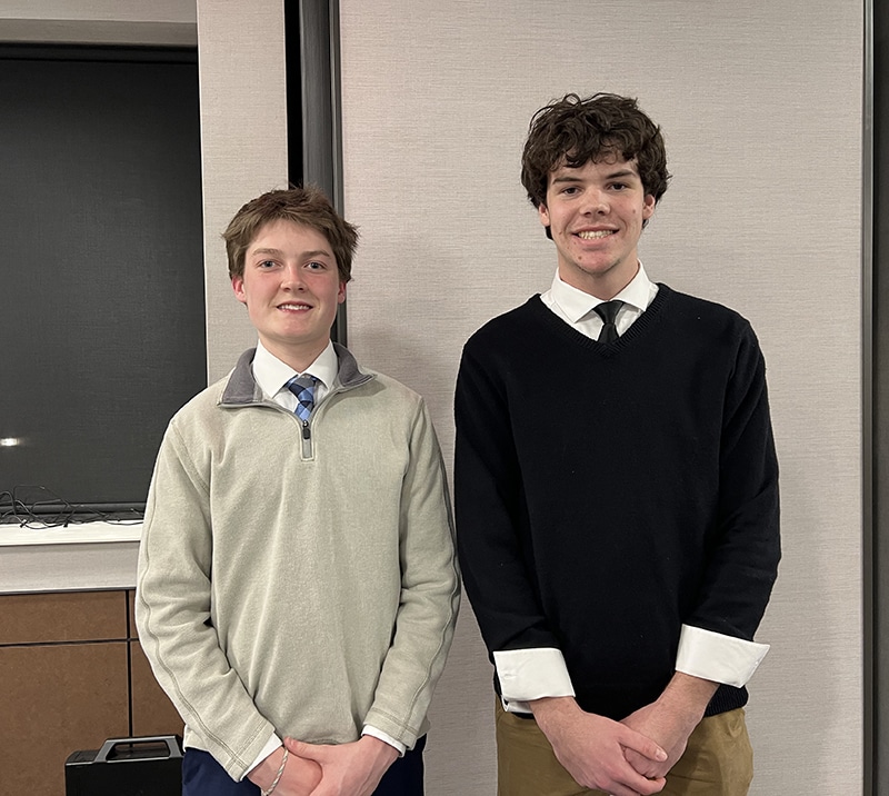 Two high school students pose against a wall.