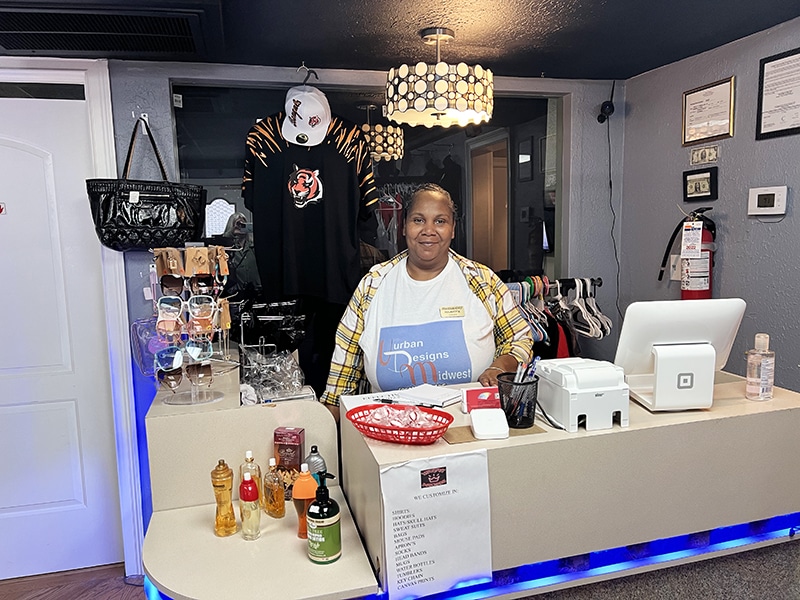 Woman stands behind counter in a clothing store.