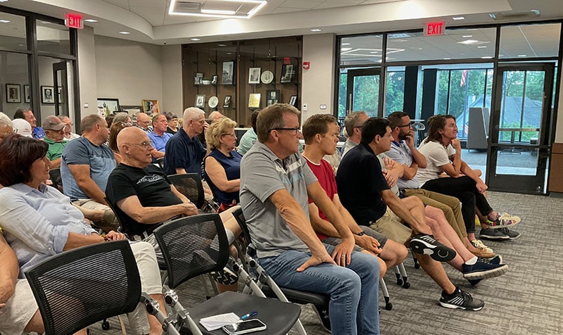About 50 people fill chairs in a meeting room.