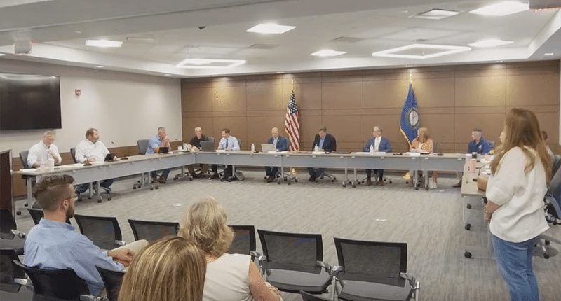 About 10 people sit at a front table at a meeting.