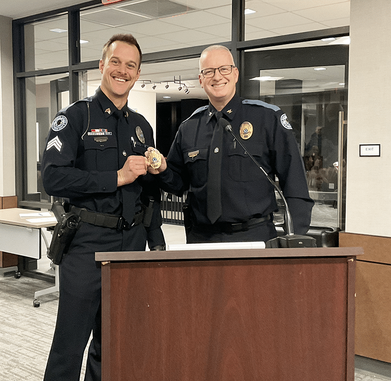 Police officer and chief of police shaking hands at podium.