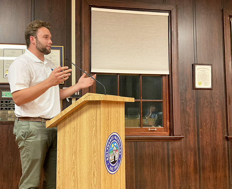 Man gestures with his hands as he stands at a podium.