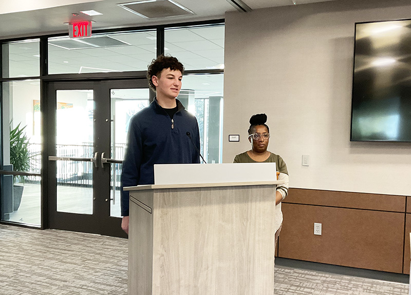 Young man stands behind a podium with a woman.