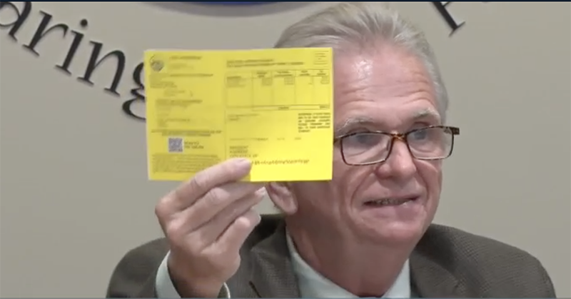 Man holds up a large yellow card.